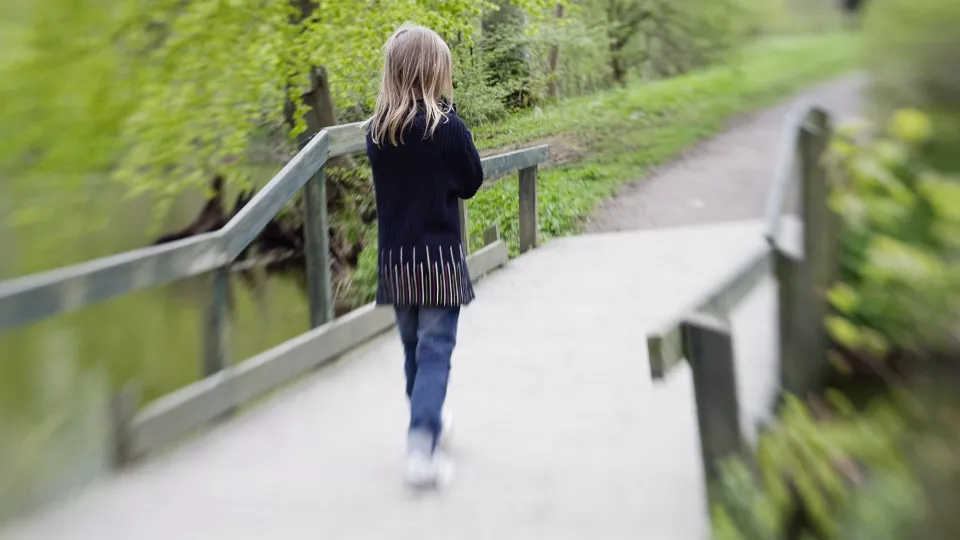 A young girl walking over a bridge.