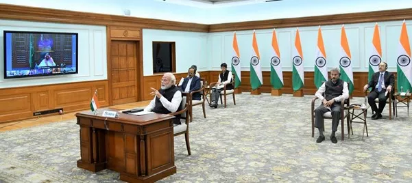 En bild från ett videomöte med Indiens premiärminister Modi. I bakgrunden finns flera indiska flaggor och fyra rådgivare sitter på vars en stol. Foto.